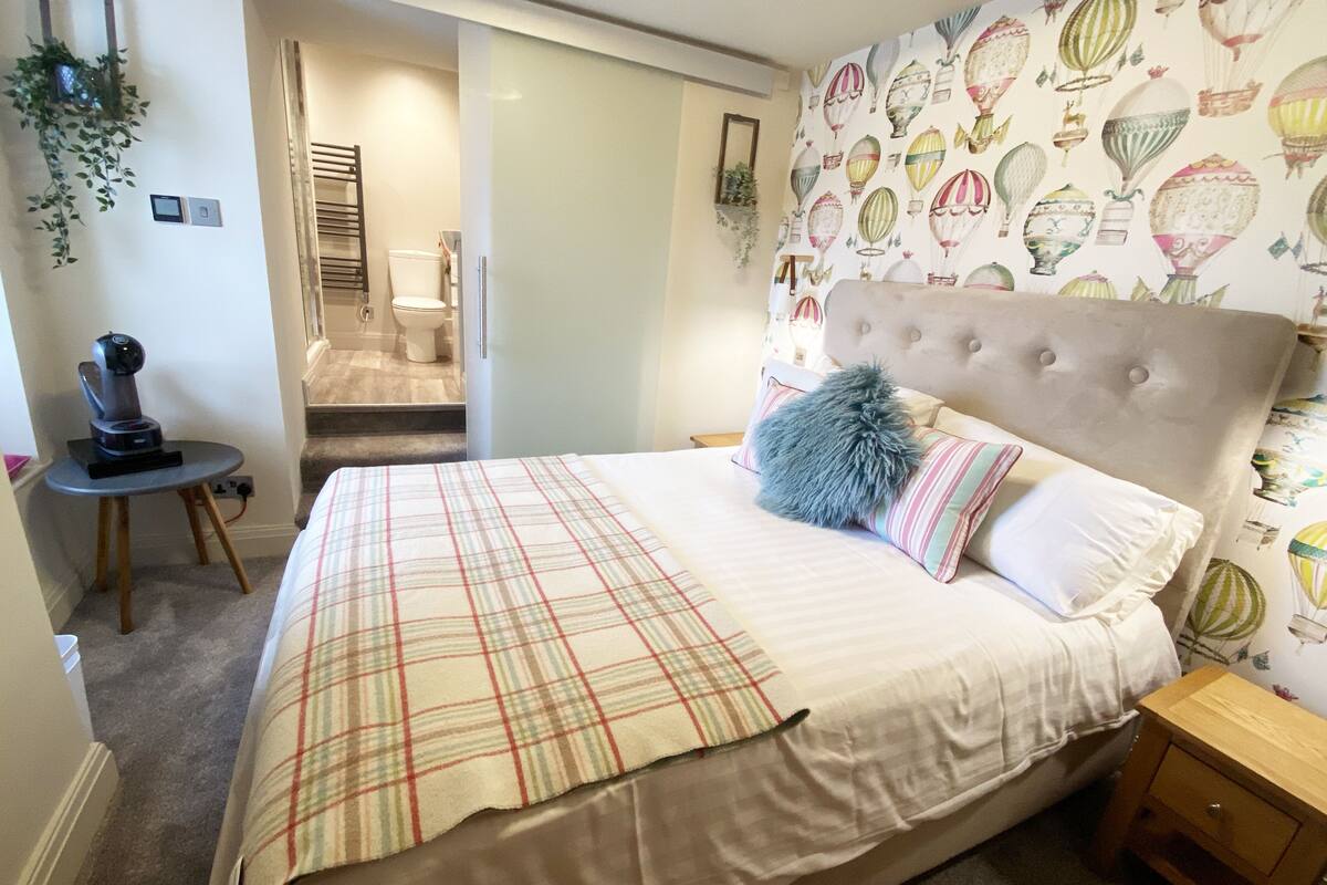 Un dormitorio con cama, una mesita de noche, un calentador de pared y ventana con vista al baño.
