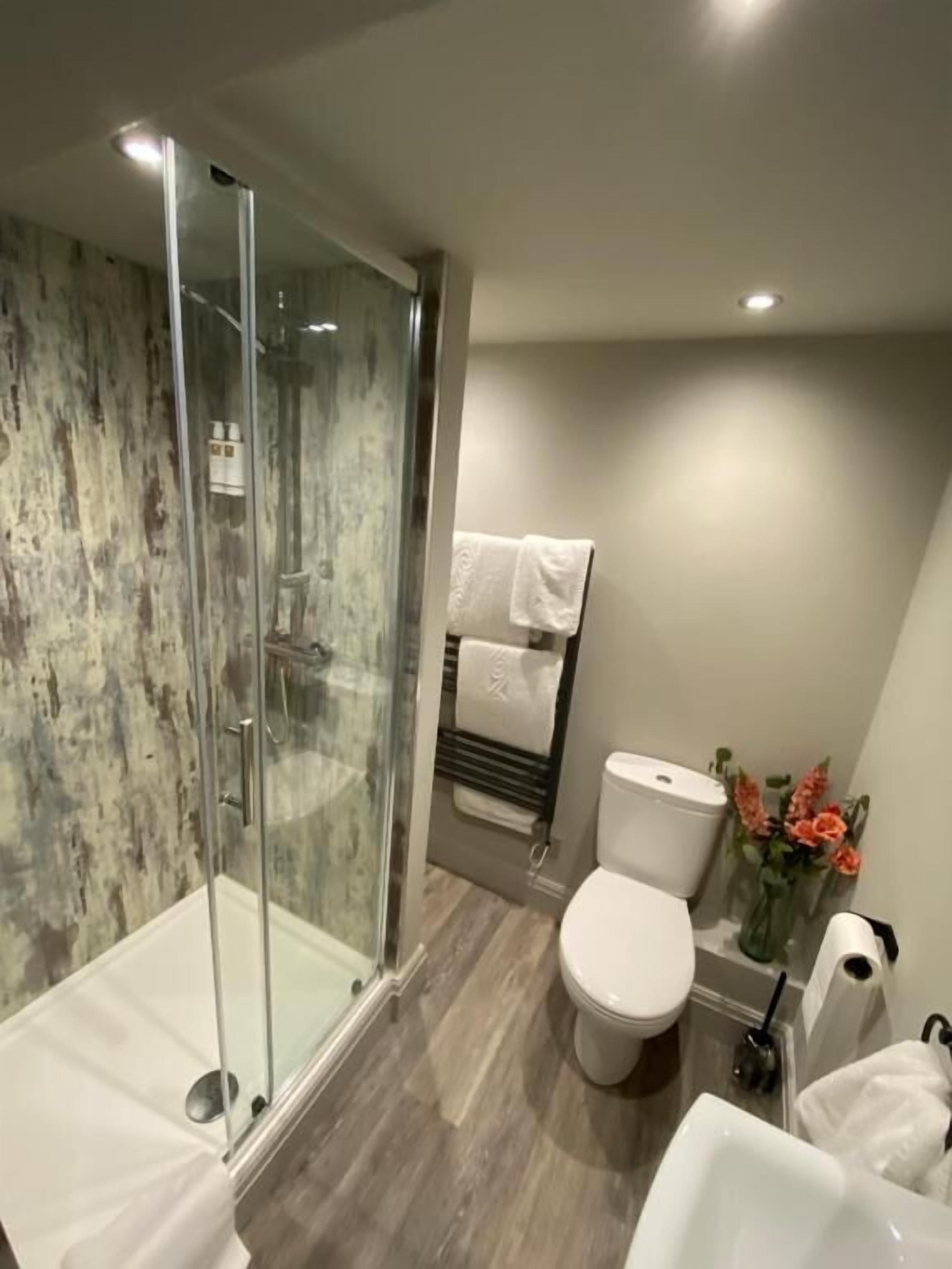 A modern bathroom with a glass-enclosed shower, a toilet, and a sink.