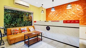 A hotel reception area with a sofa, a small table, and a wall with a sign. - Itsy Hotels Transit Express Near Sealdah Station (Kolkata)
