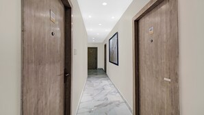 A hallway with wooden doors, numbered signs, and a marble floor. - Itsy Hotels Transit Express Near Sealdah Station (Kolkata)