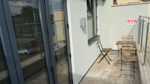 A room with a sliding glass door, a small wooden bench, and a metal table.
