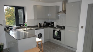 A modern kitchen with a built-in washing machine, a stove, and a microwave.