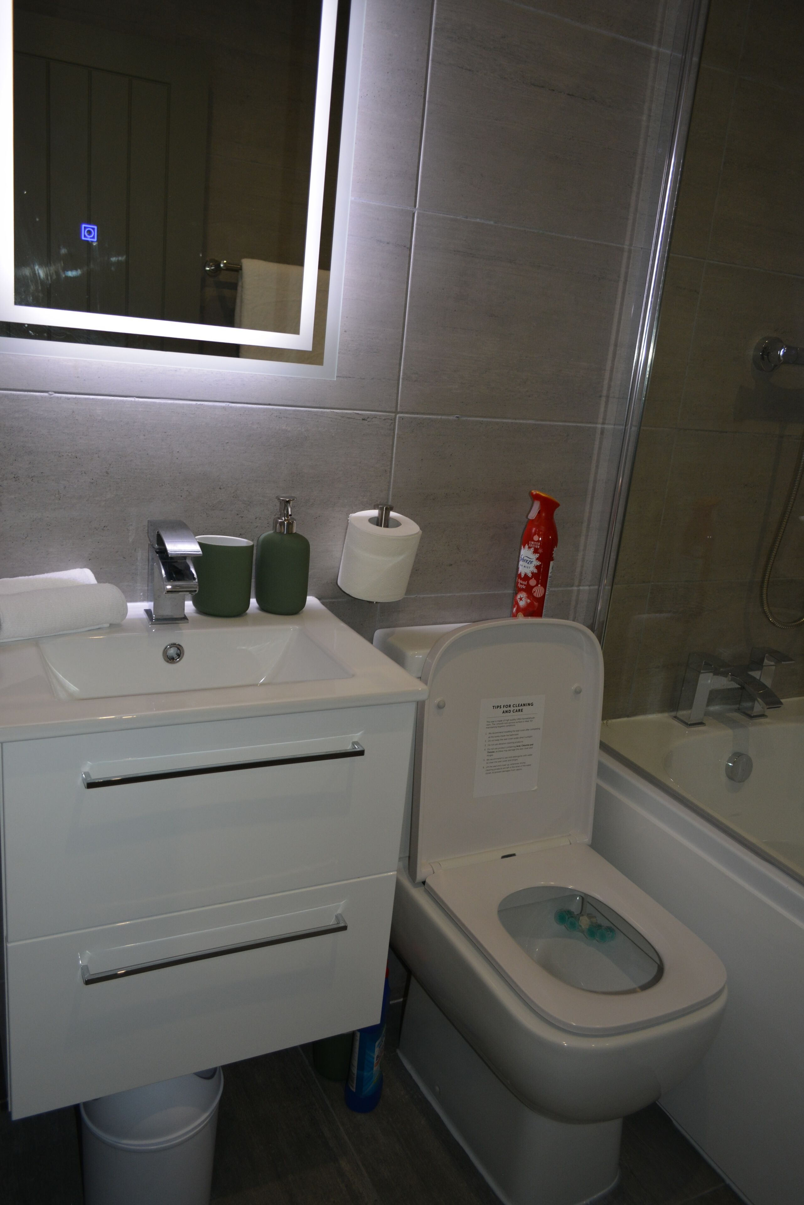 Ein Badezimmer mit Waschbecken, Spiegel, Toilette und Dusche.