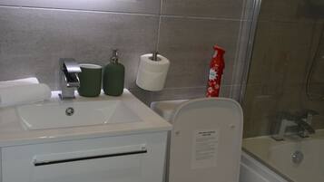 Ein Badezimmer mit Waschbecken, Spiegel, Toilette und Dusche.