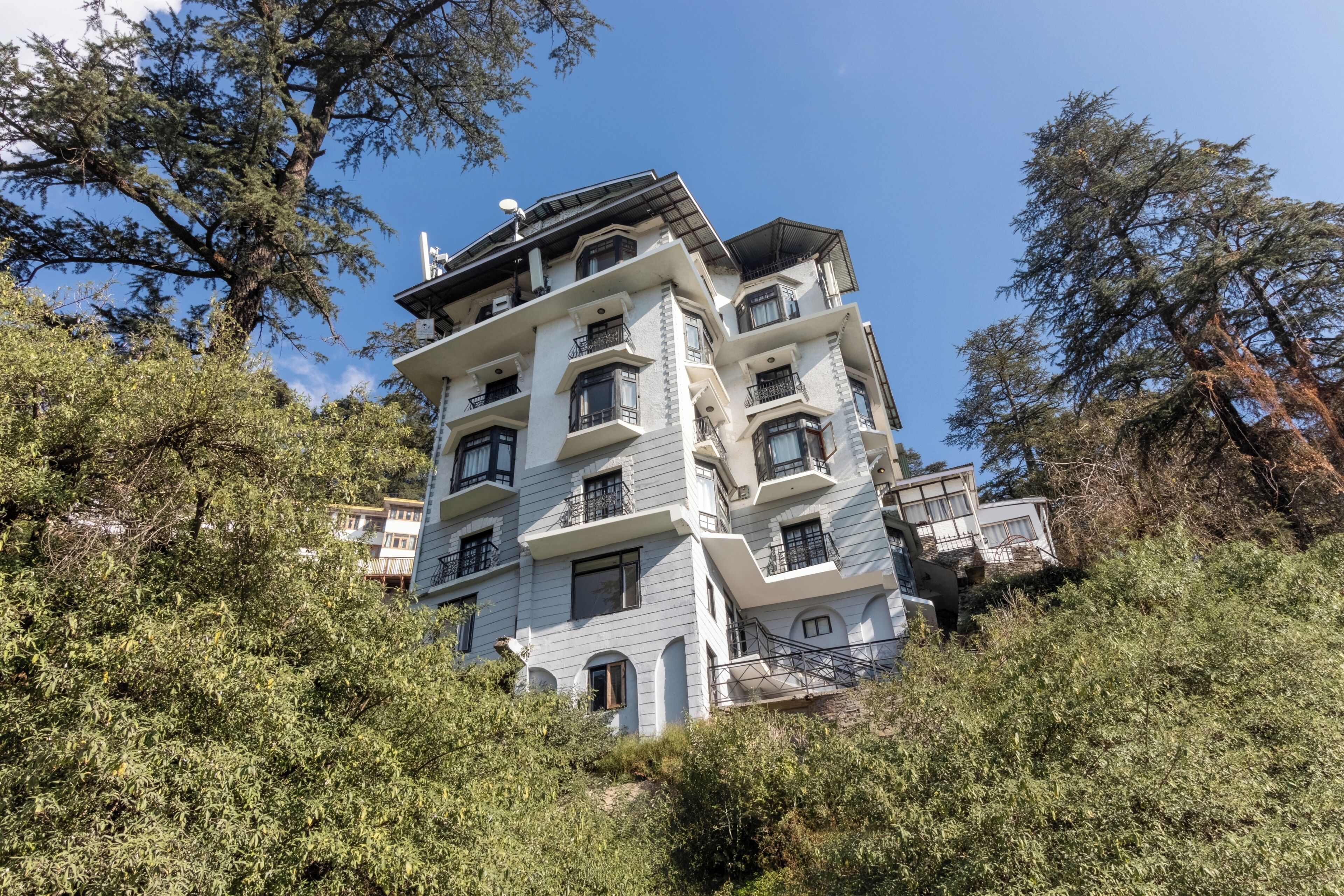 Un edificio de varios pisos con balcones, rodeado de árboles.