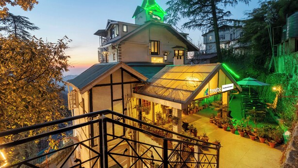 A hotel with a steep staircase, a green-lit roof, and a sign for 'treebo.' - Treebo The Alpine Heritage Residency (Shimla)