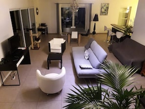 A modern living room with a sofa, armchair, and a dining table.