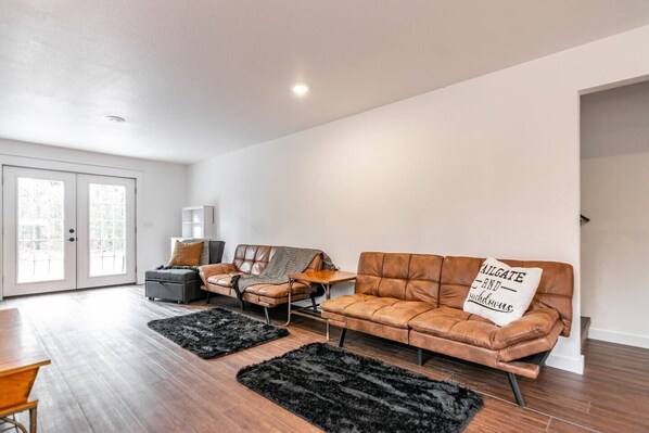 A modern living room with a brown leather sofa, a grey armchair, and a black rug.