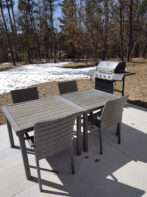 Un patio exterior con una parrilla y muebles de mimbre.
