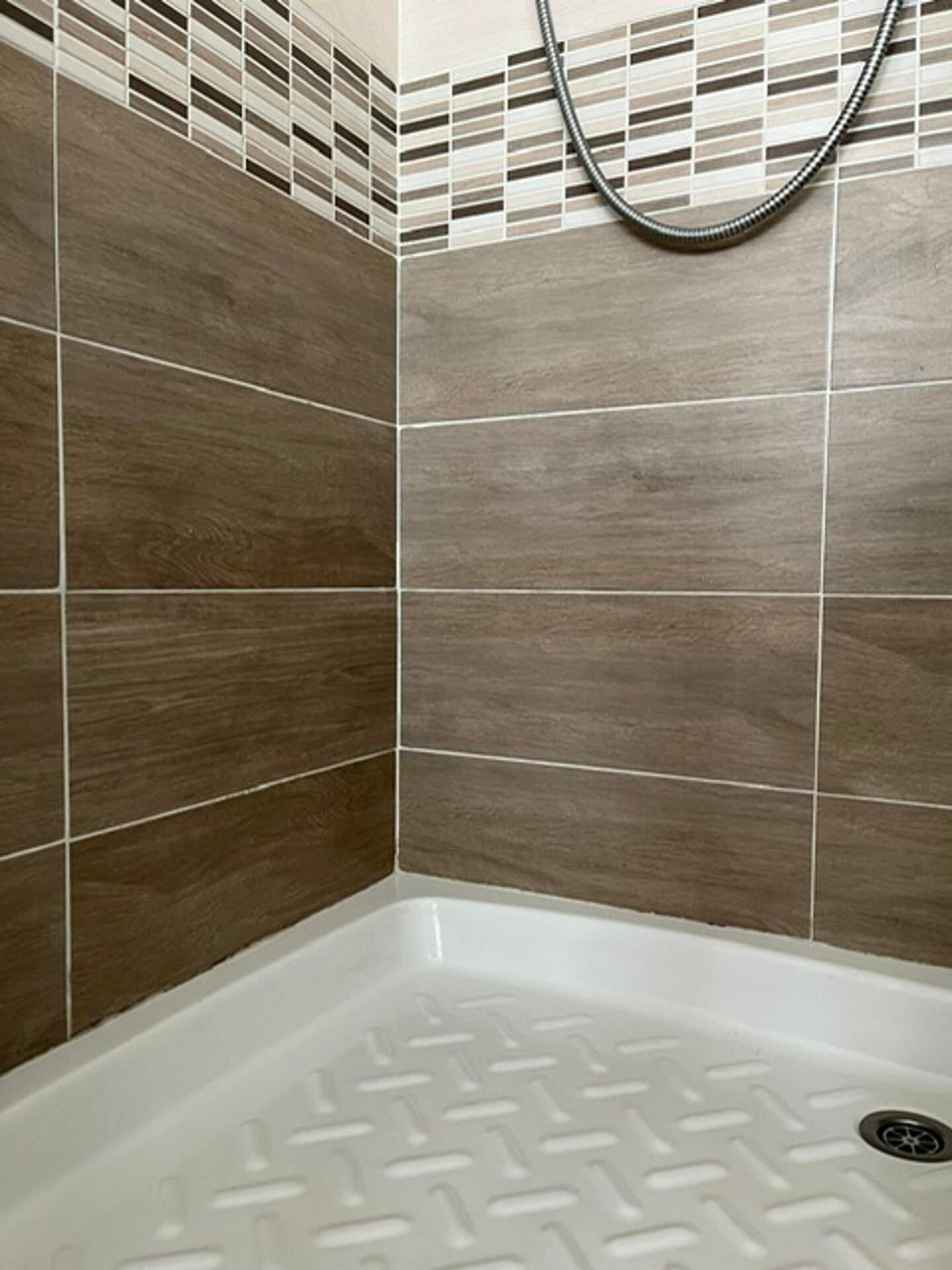 Un espace douche avec des carreaux marron et une baignoire blanche.