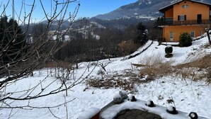 A two-story building with a balcony, surrounded by snow-covered landscape and mountains in the background. - Cosy, pet Friendly Apartment in Portula, Italy (Portula)