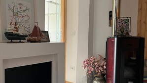A living room with a fireplace, a decorative map, a vase with flowers, and a modern stove. - Cosy, pet Friendly Apartment in Portula, Italy (Portula)