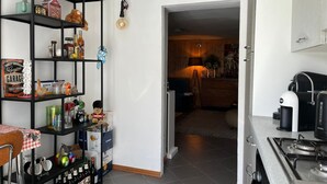 A kitchen with a gas stove, a coffee maker, and a shelf with various items including a toy car and a bottle of Corona Extra. - Cosy, pet Friendly Apartment in Portula, Italy (Portula)