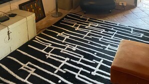 A room with a large flat-screen TV on a cabinet, a patterned rug, a red chair, and a hanging light fixture. - Cosy, pet Friendly Apartment in Netro, Piedmont (Netro)