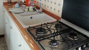 A kitchen with a gas stove, white cabinets, a sink, and a backsplash with a blue and white pattern. - Cosy, pet Friendly Apartment in Netro, Piedmont (Netro)