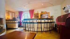 A cozy bar area with a counter, stools, and a variety of bottles. - Ô Caprice du Guiers (Saint-Pierre-de-Chartreuse)