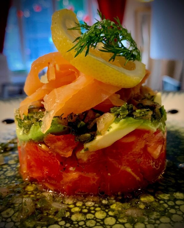 Un plato con capas de ingredientes, adornado con limón y hierbas.