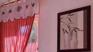 A bedroom with a bed, red and white curtains, a framed picture on the wall, and a wooden headboard. - Ô Caprice du Guiers (Saint-Pierre-de-Chartreuse)