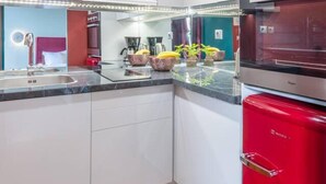Eine moderne Küche mit weißen Schränken, einem roten Kühlschrank und Edelstahlgeräten.