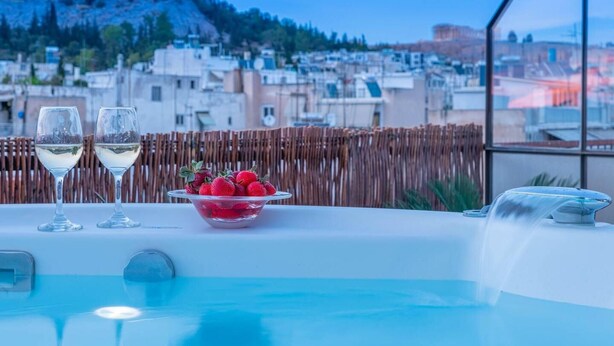 Ein Whirlpool mit Blick auf eine Skyline, zwei Gläser Weißwein und eine Schale Erdbeeren.