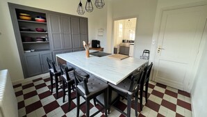 A kitchen with a large island, dark chairs, a checkered floor, and a white door.