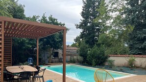 A wooden deck with a pool, outdoor furniture, and a pergola.