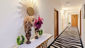 A hallway with a mirror, decorative vases, a small table, and a zebra-patterned carpet. - Treebo Premium Widlor Boutique (Mumbai)