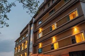 A multi-story building with illuminated windows, a visible staircase, and a clear sky.