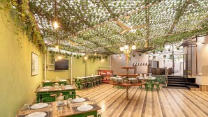 A restaurant with wooden tables and chairs, a green color scheme, and a ceiling covered in greenery. - Treebo Premium Widlor Boutique (Mumbai)
