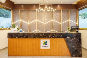 A reception desk with a logo, a wooden panel, and a marble countertop.