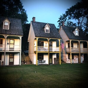A row of two-story houses with balconies, a flag, and a staircase leading to the entrance. - Cozy, unique, historic registered cottage on the Corsica River! (Centreville)