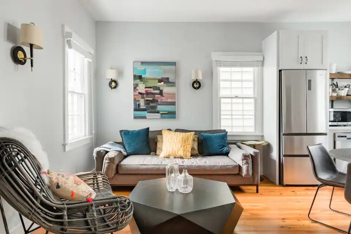 A modern living room with a sofa, a coffee table, and a wicker chair.