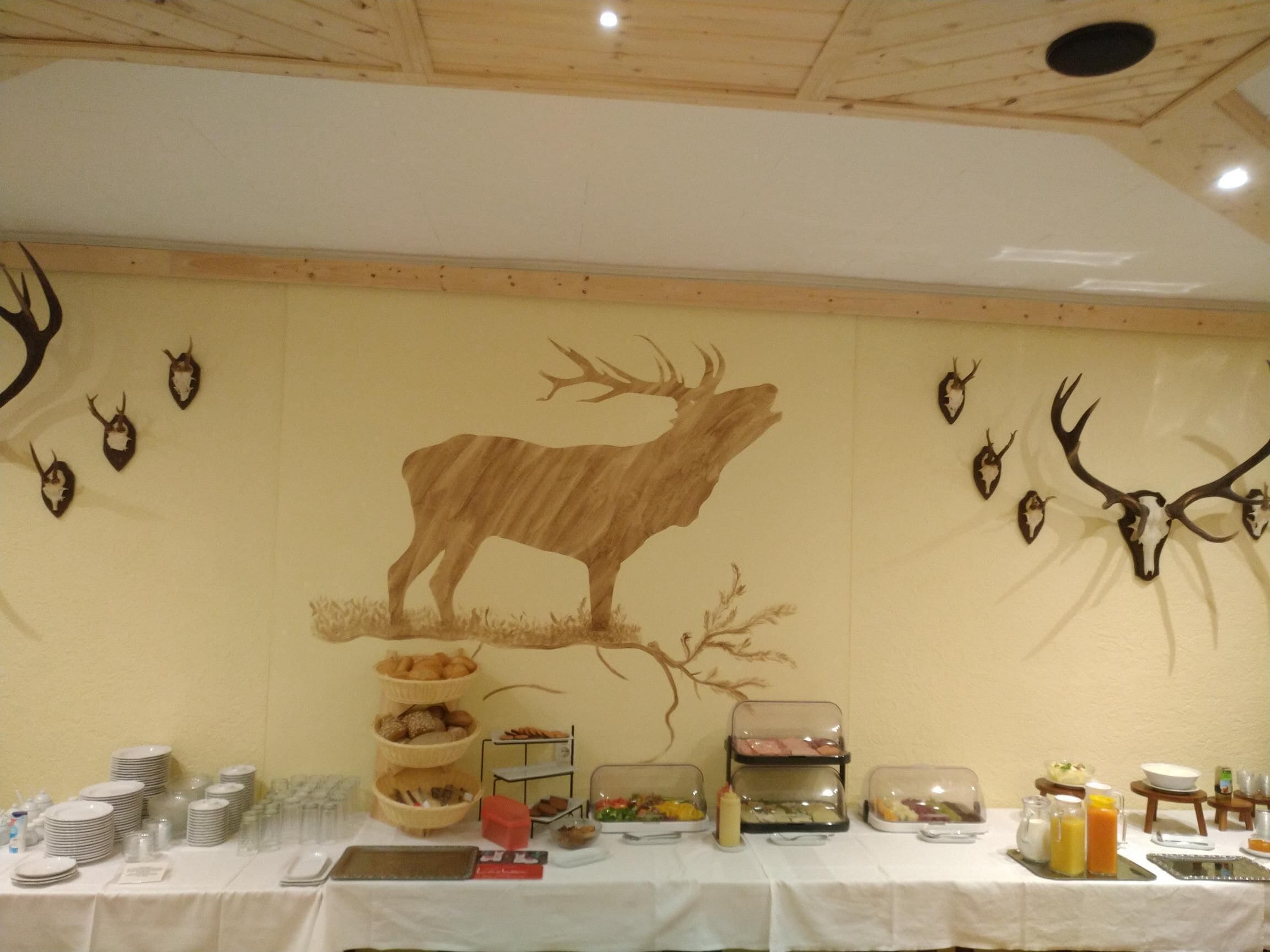 Ein reichhaltiges Buffet mit einer großen Wandmalerei von einem Hirsch, umgeben von verschiedenen Speisen und Geschirr.