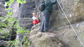 A person climbing a rocky cliff with a rope.