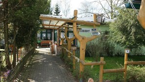 A wooden pergola structure with a sign indicating a restaurant named "Zimmer" and a directional sign pointing to the right.