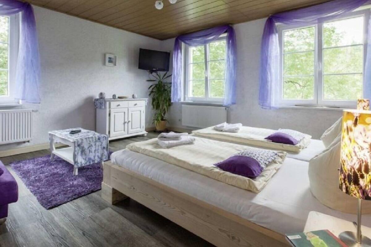 Una habitación con dos camas, televisión, una mesita y una lámpara.