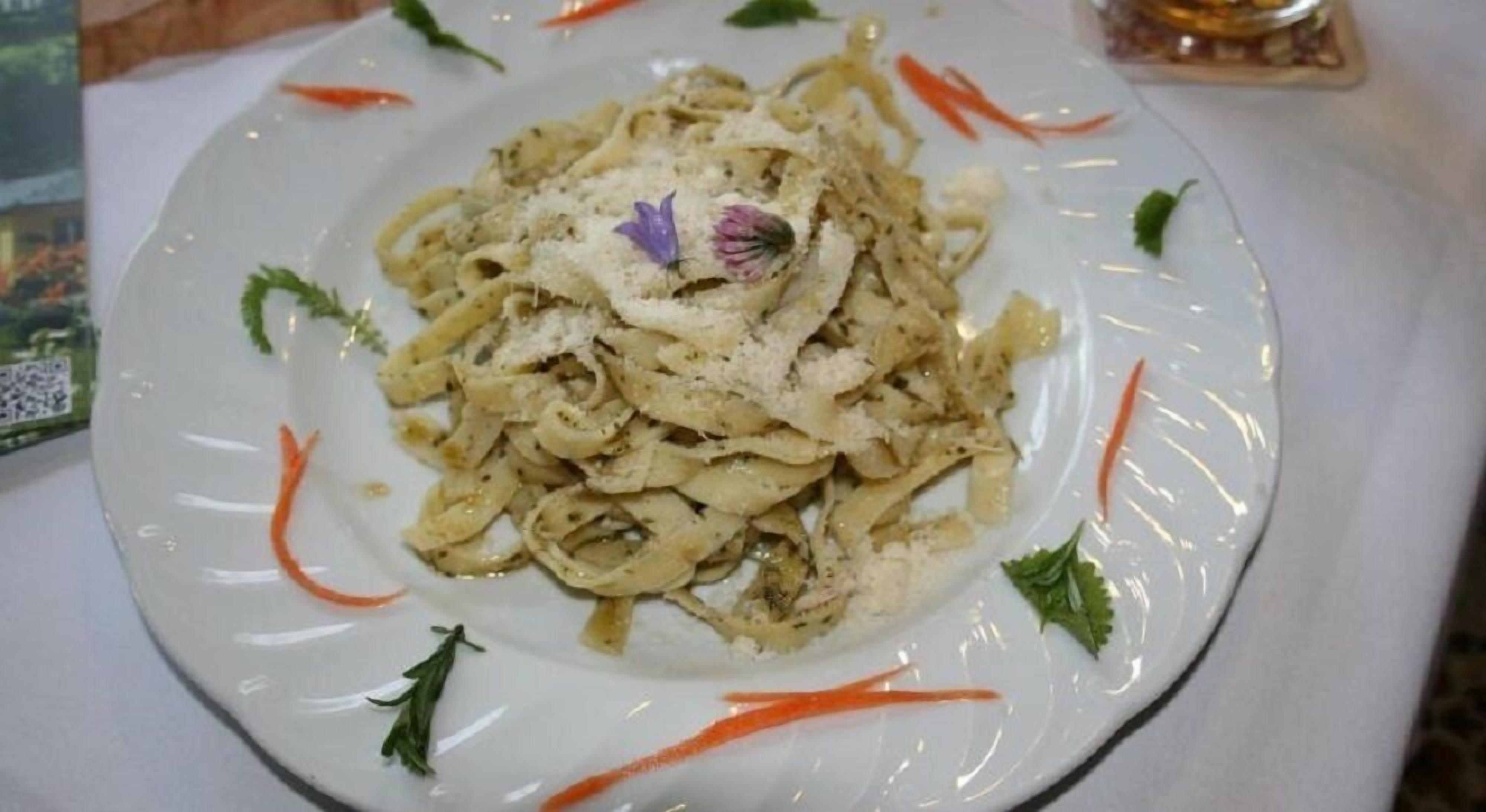Un plato de pasta decorado con hierbas y una flor ornamental.