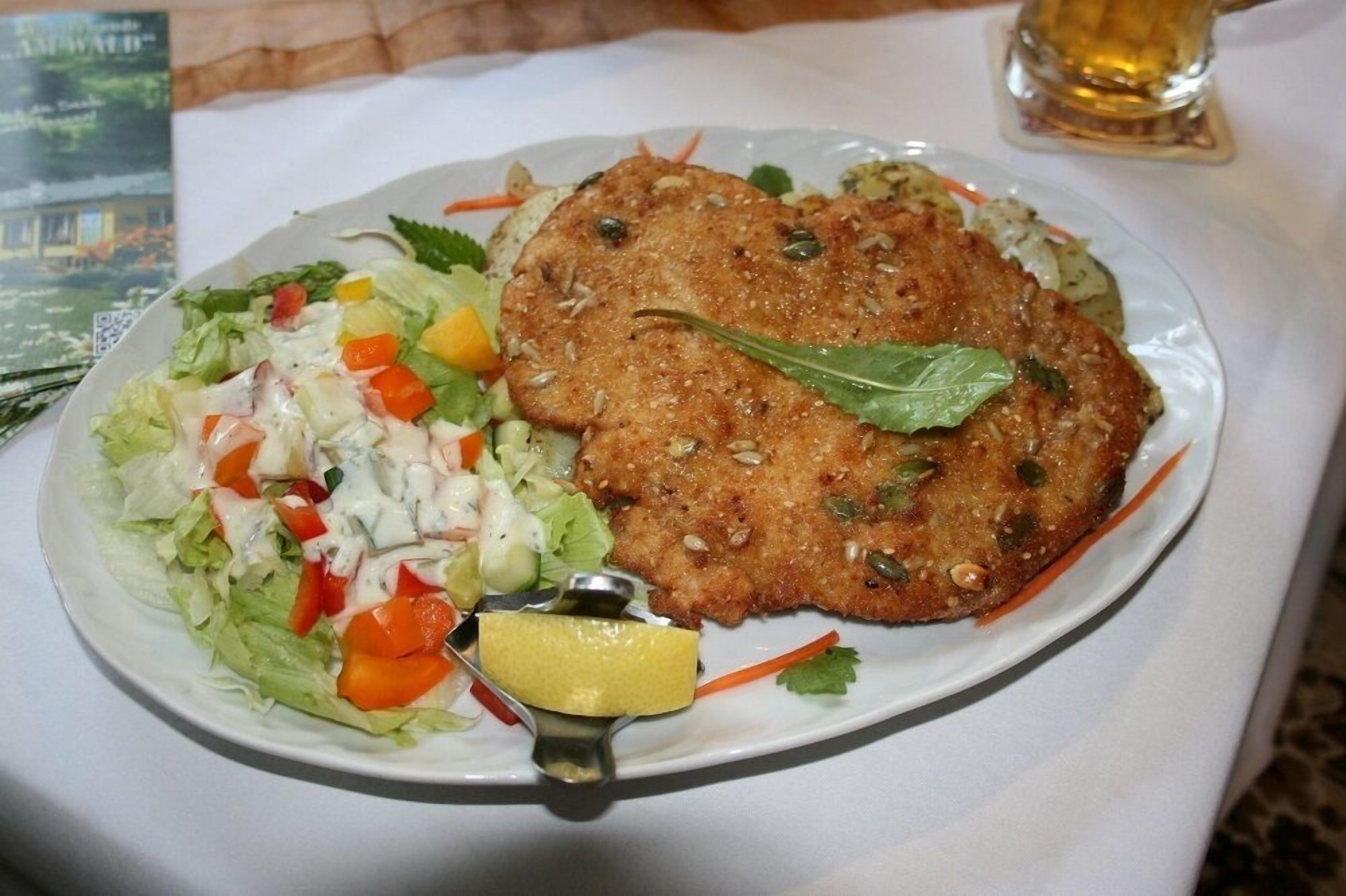 Un plato con una milanesa, ensalada y una rodaja de limón.