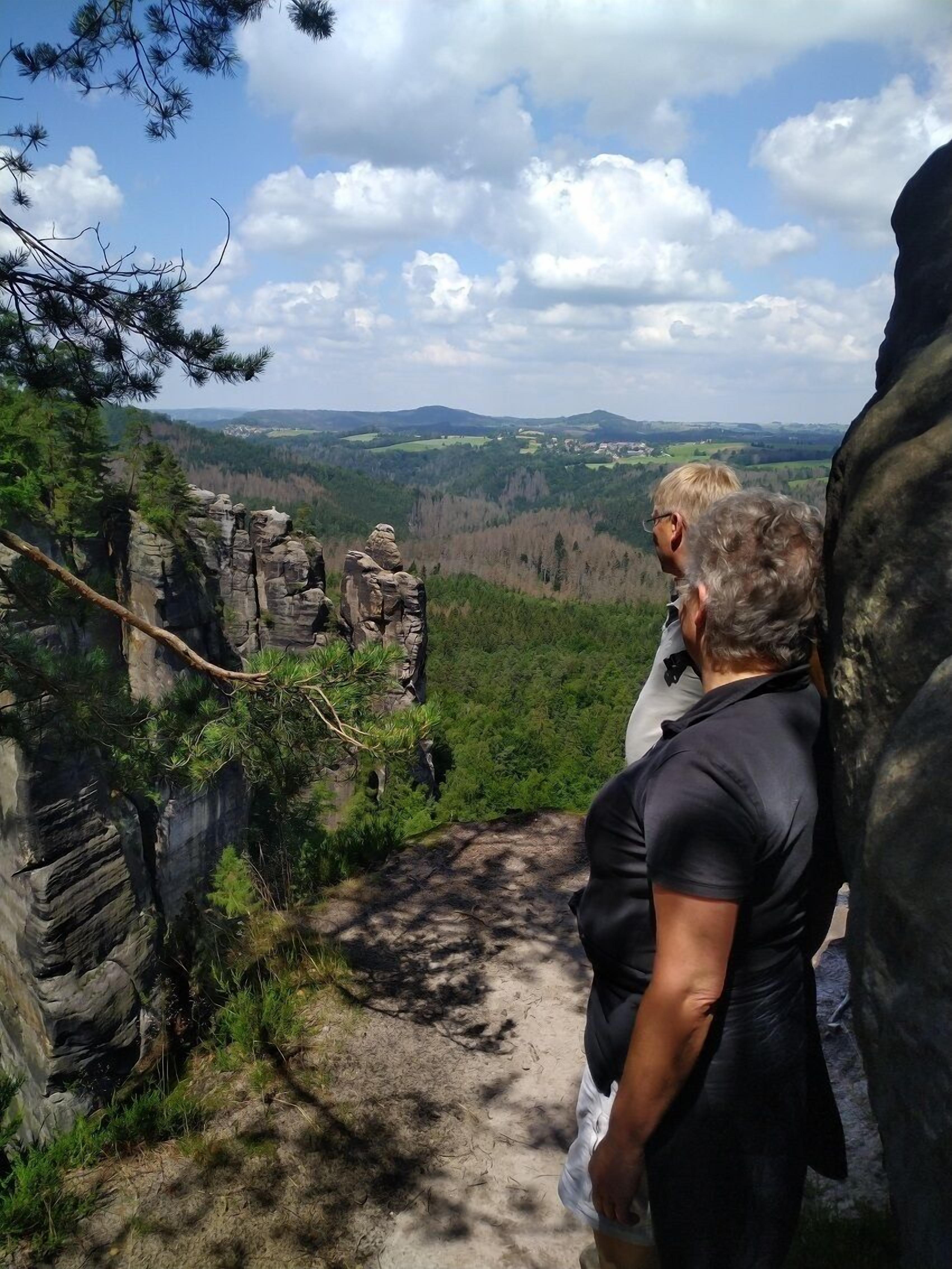 A rocky terrain with a clear view of a valley and distant buildings.