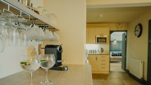 A kitchen with a coffee machine, a countertop with wine glasses, and a wooden cutting board. - Rural Holiday Cottage With Log Burner (Buxton)