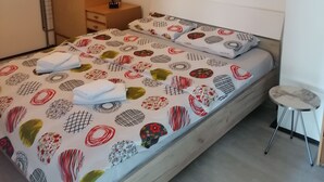 Un dormitorio con cama, mesita de noche, una silla, armario y un cuadro en la pared.