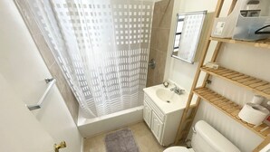 A compact bathroom with a shower curtain, a sink, a toilet, and a shelf with toiletries. - GREAT UPPER MANHATTAN APARTMENTS FOR GROUP AND FAMILIES (new york)