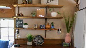 A rustic wooden table with a bench, shelves with plants and decorative items, and a sign that reads "amazing grace". - Meadow View Cottage (Manheim)