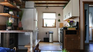A kitchen with wooden beams, a refrigerator, a stove, and a dining table with a plate of cookies. - Meadow View Cottage (Manheim)