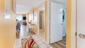Un pasillo con piso de baldosas, un tapete colorido y una puerta que da a una habitación.