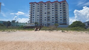 Un hotel de varios pisos con balcones, situado cerca de una playa de arena.