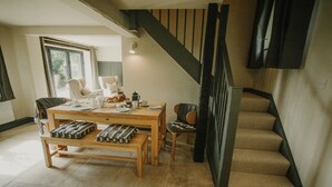 A dining area with a wooden table and benches, a staircase, and a view of the outdoors. - Luxury Rural Holiday Cottage With Log Burner (Buxton)