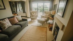 A modern living room with a grey sofa, patterned cushions, a beige armchair, and a coffee table. - Luxury Rural Holiday Cottage With Log Burner (Buxton)