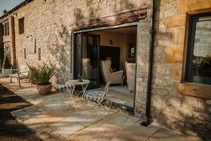 Un edificio in pietra con un patio che include un tavolo, sedie e una pianta in vaso.