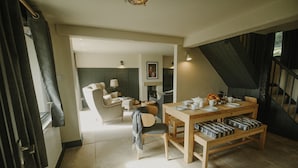 A dining area with a wooden table, chairs, and benches. There is a staircase leading to an upper level. - Luxury Rural Holiday Cottage With Log Burner (Buxton)